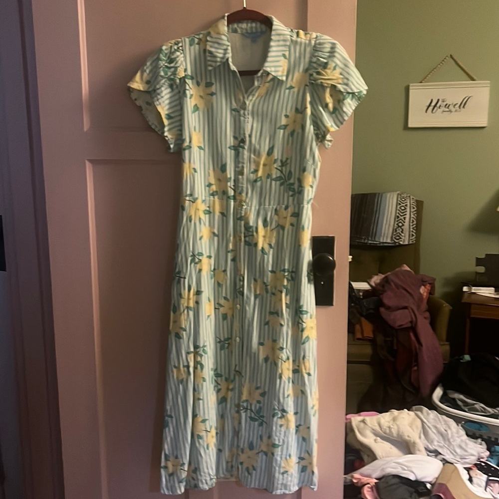 This is a 1920s style dress. It’s white with green stripes and yellow flowers.